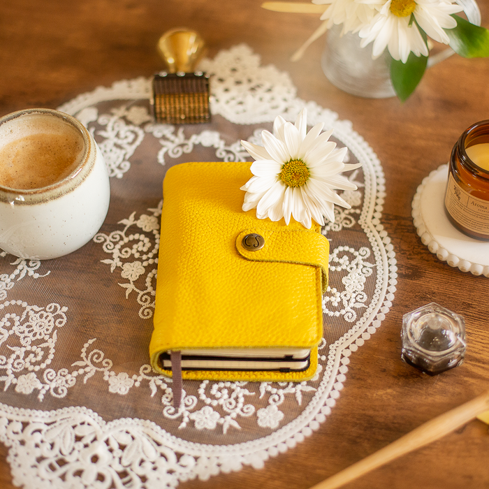 A leather notebook on a table with some arrangements.
