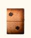 This is an example of what antiquing looks like on an Emma. Antiquing is when an artist applies dye to make markings like splatters and cup rings on a leather notebook to make it look older.