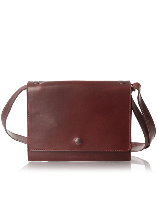 An Austen leather trifold with a snap closure and adjustable strap. This is a bag-notebook hybrid. The collection name is Austen and the color is called Drummond (Burgundy)- ChicSparrow