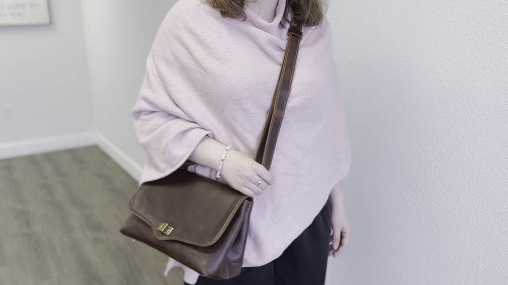 video showing a person wering the bag cross body,  the adjustable straps makes it so the person can wear it according to their comfort level,  also the strap can be removed and held by the top handle.